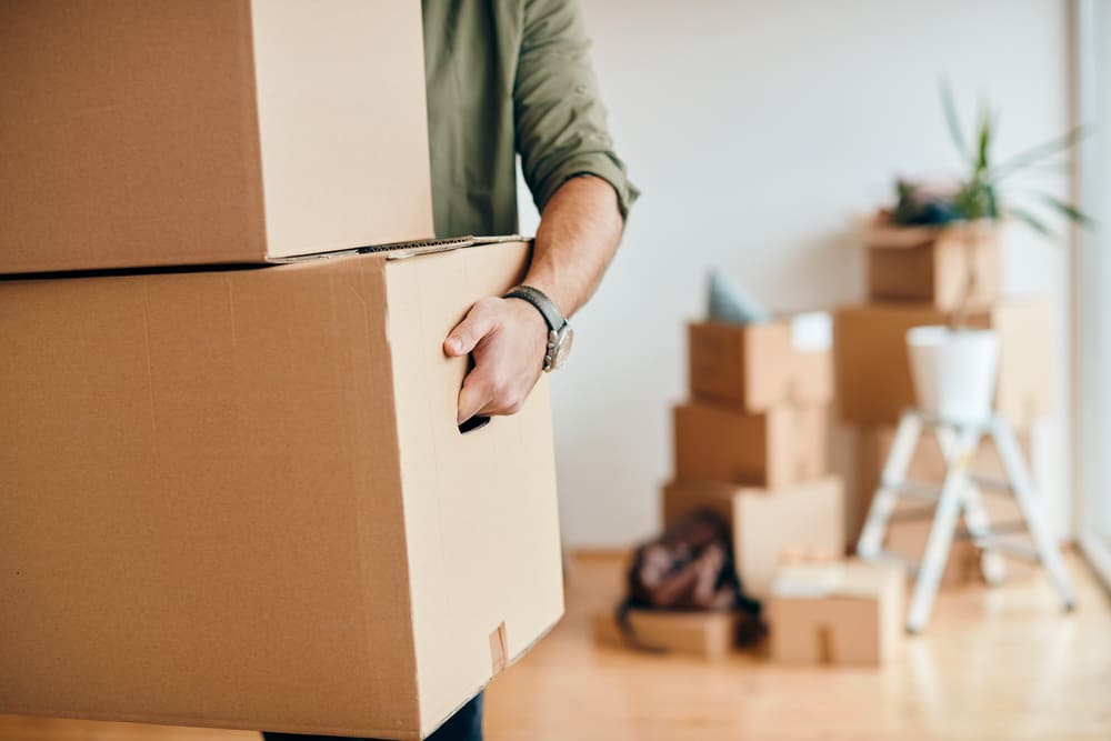 Primer plano de un hombre que lleva cajas de cartón mientras realiza una mudanza a un nuevo apartamento